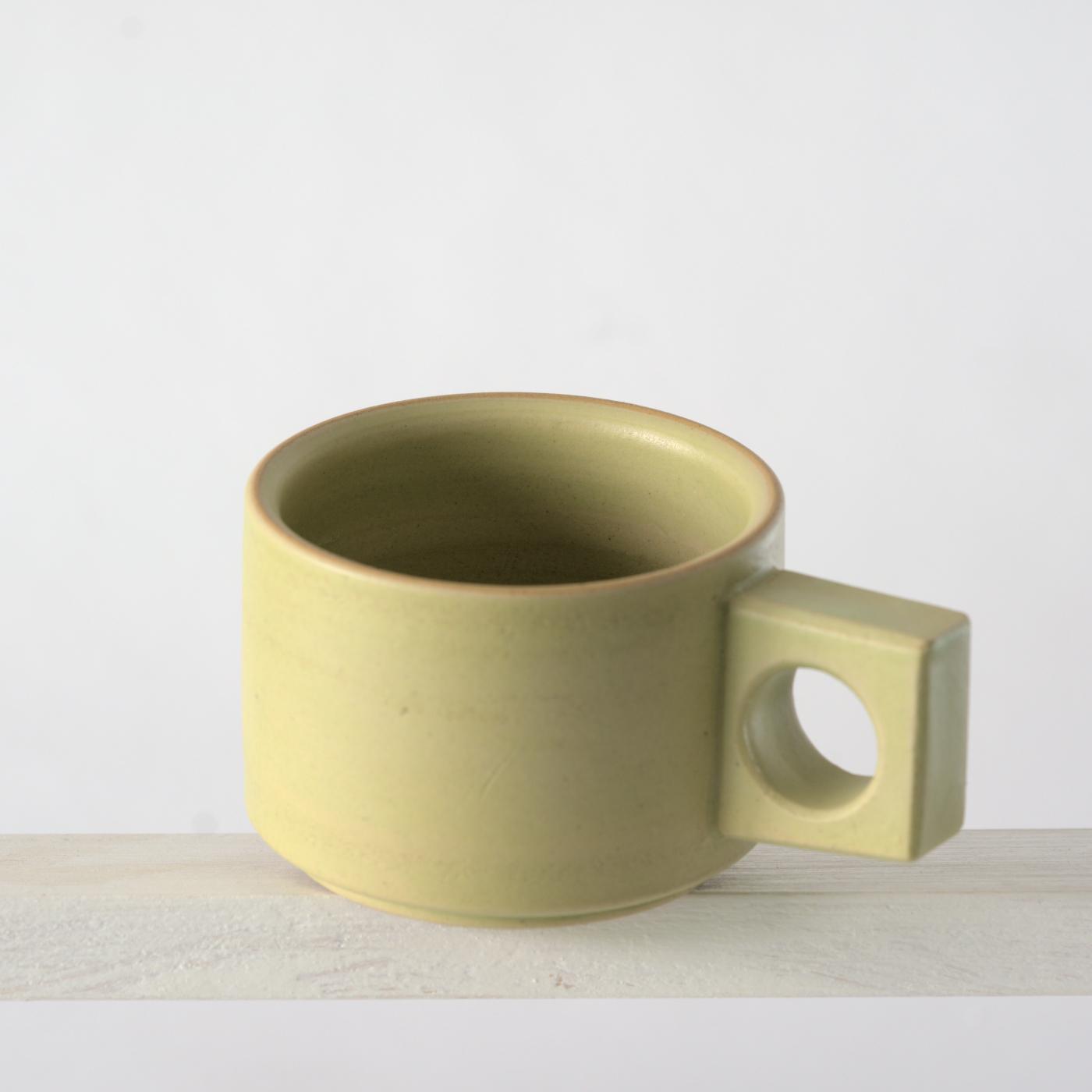 Schräge Aufsicht auf eine kleine Tasse mit einer matten, limone Glasur