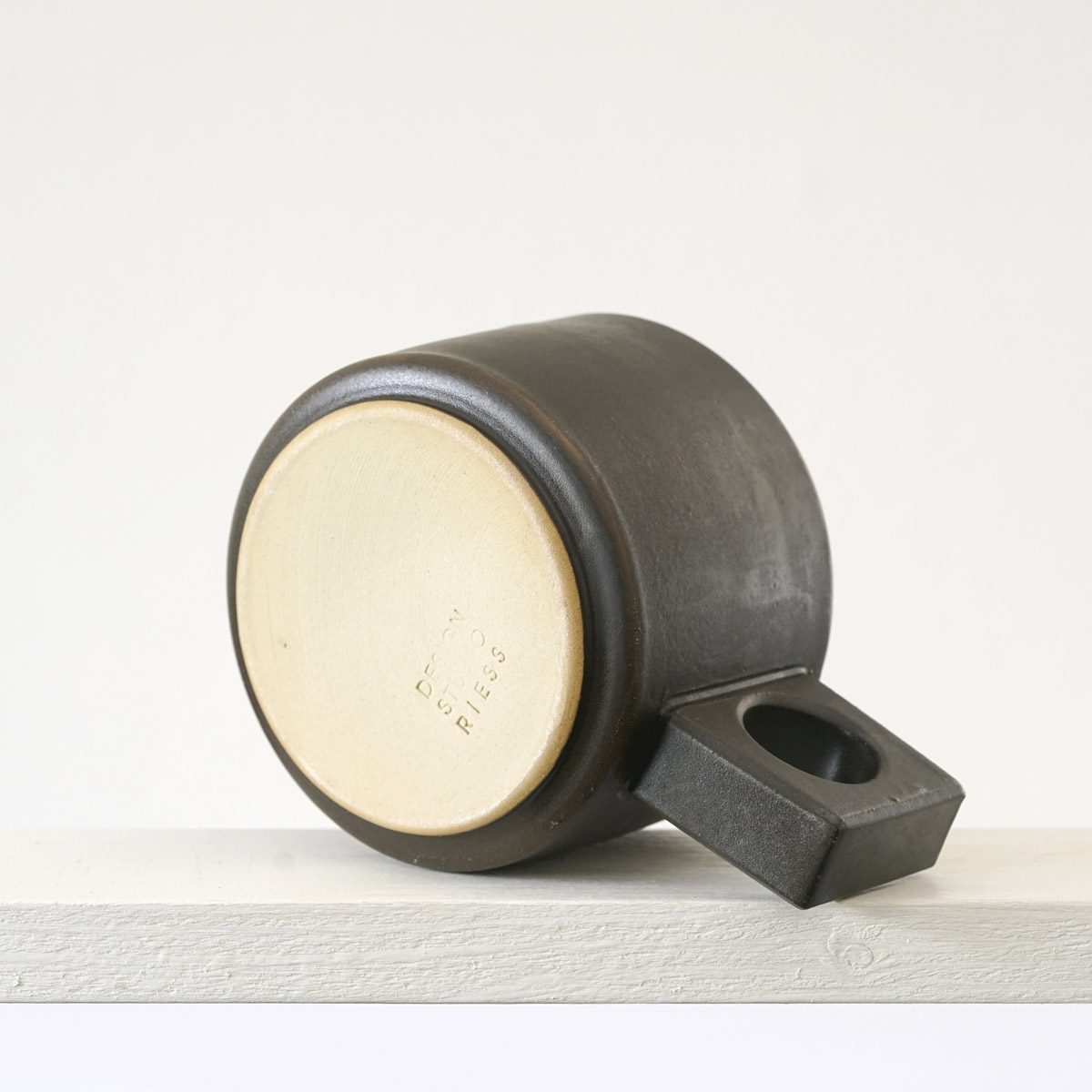 Unteransicht einer kleinen Tasse mit einer matten, dunklen mokkafarbenenfarbenen Glasur