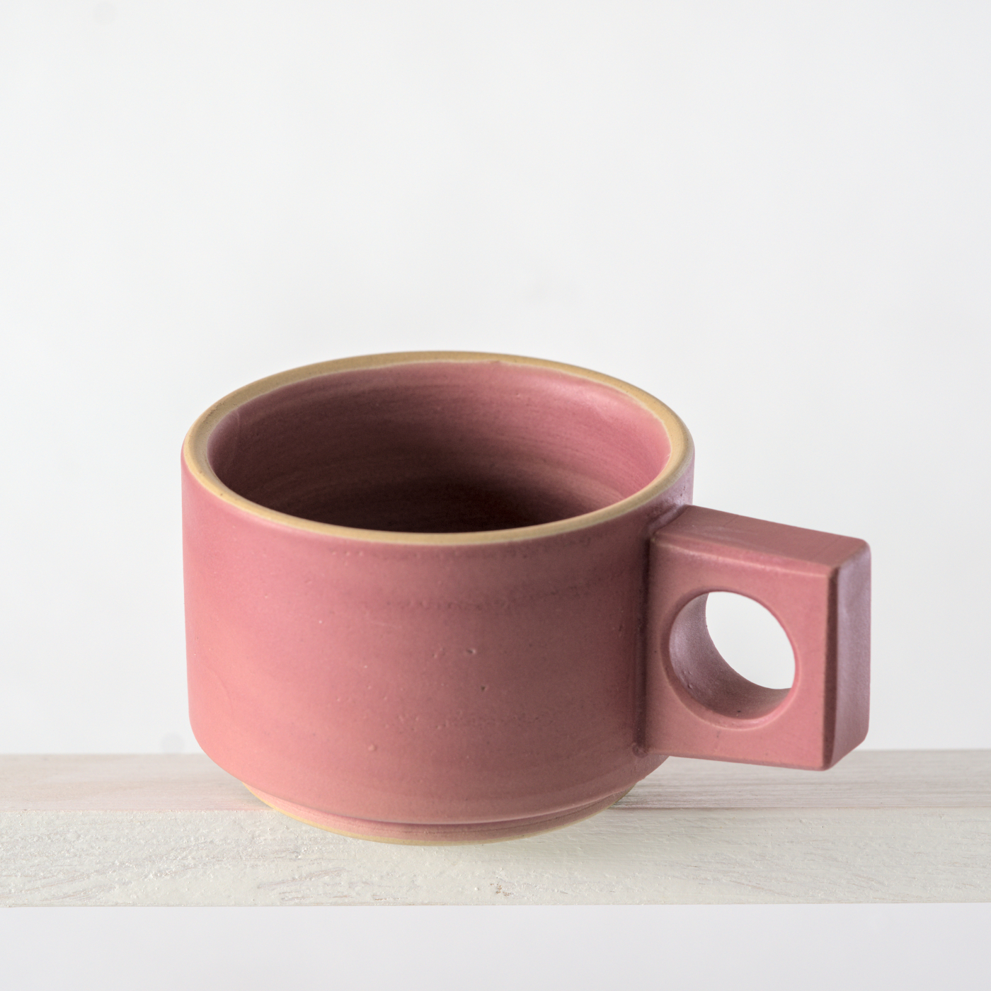 Schräge Aufsicht auf eine kleine Tasse mit einer matten, rosa Glasur