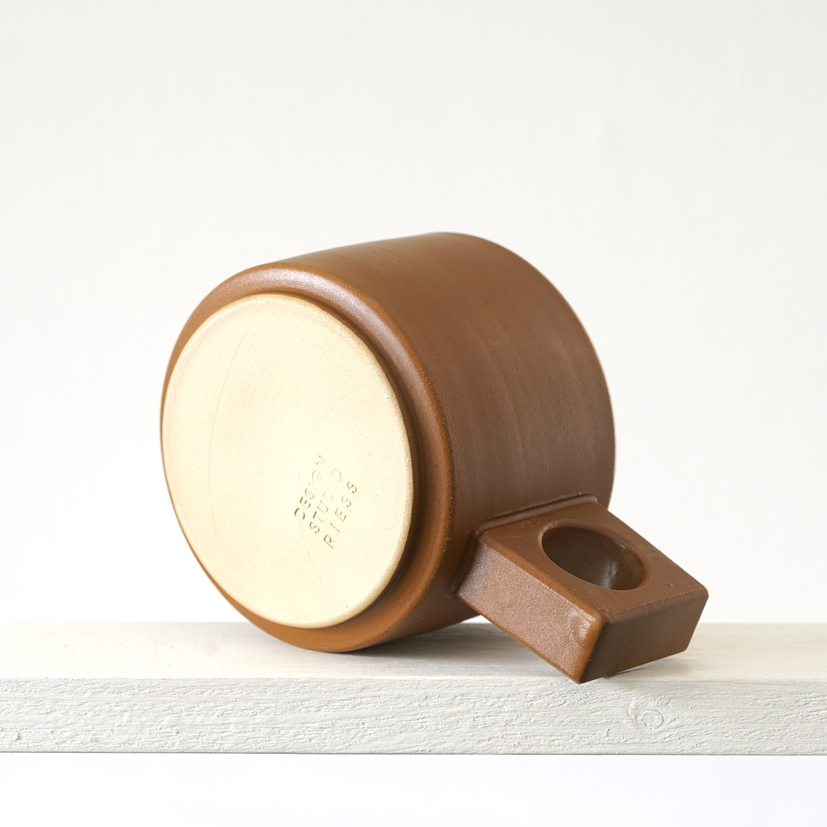 Unteransicht einer kleinen Tasse mit einer matten, zimtfarbenen Glasur